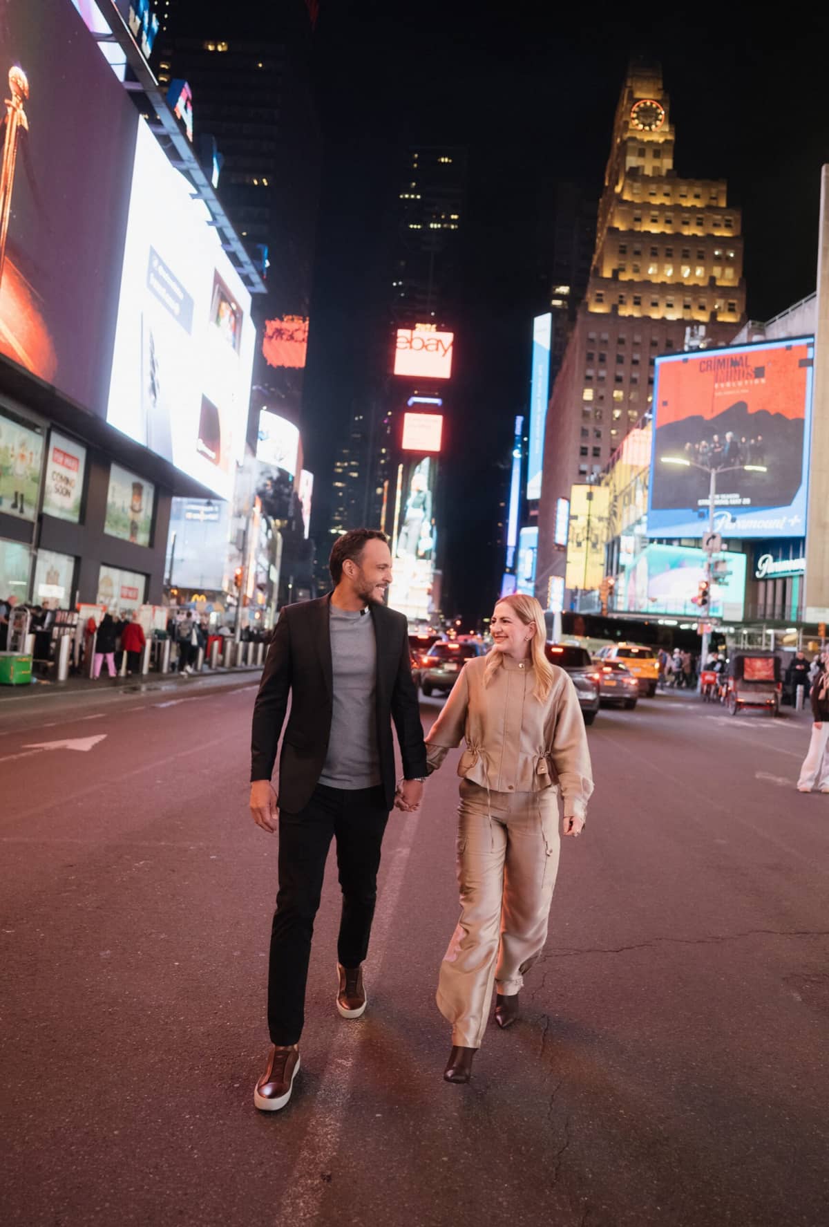 Paty e Fred caminhando de mãos dadas por Times Square, à noite